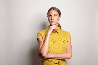 Serious clever confident successful business woman looking at camera against grey studio wall background with copy space