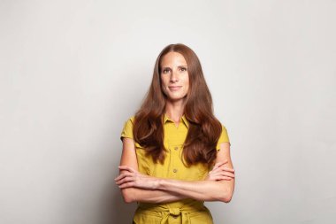 Beautiful confident woman in yellow clothes standing with crossed arms, indoor portrait