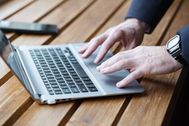 Dizüstü bilgisayarda çalışan iş adamı elleri. Tahta masaya yaklaş.