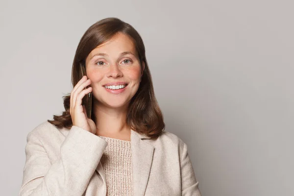 Attraktive Junge Frau Telefoniert Und Lächelt Vor Grauem Studiowand Hintergrund — Stockfoto