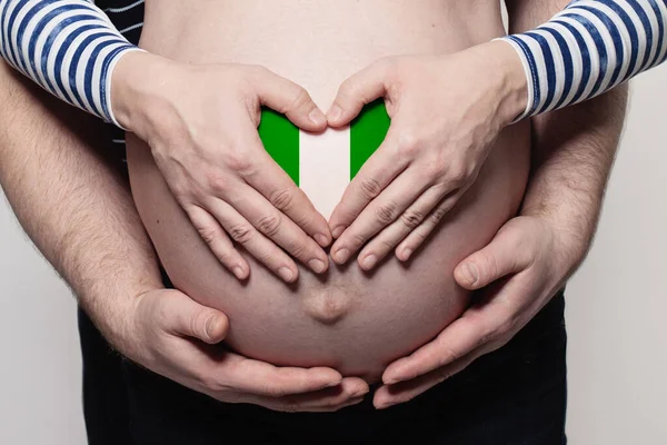 家庭概念 与尼日利亚国旗颜色特写的男人拥抱孕妇的肚子和心脏 — 图库照片