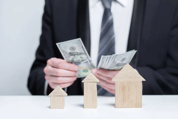 Wooden house models and us money dollars in businessman hands, byuing property, security, insurance concept