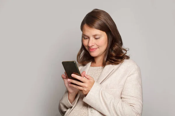 灰色の背景に携帯電話を使用して幸せな魅力的な妊婦 — ストック写真