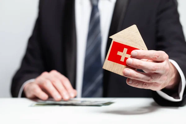 商人手拿着印有瑞士国旗的木制家用轿车模型 保险和财产概念 — 图库照片