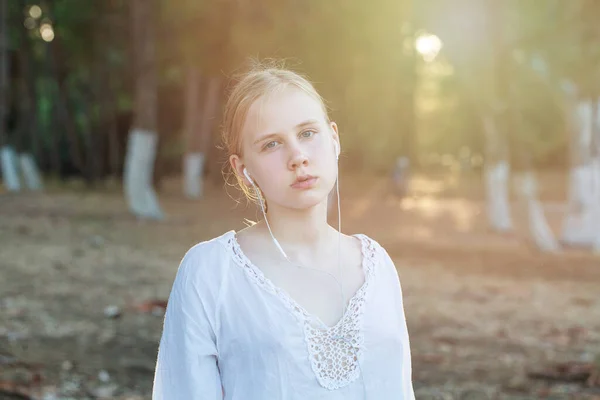 Blondynka Nastolatka Białej Koszuli Słuchać Muzyki Słuchawkach Tle Lasu Światła — Zdjęcie stockowe