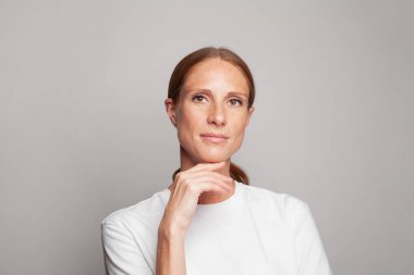 Güzel, olgun bir kadın modelin portresi. Orta yaşlı bir kadının eli yüzünün yanında.