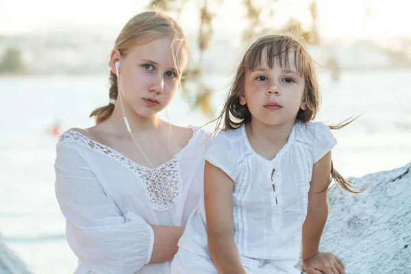 海を背景に木の上に座っている二人の姉妹 子供と十代の女の子 — ストック写真
