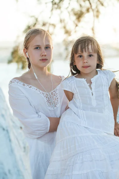 Duas Irmãs Criança Adolescente Sentadas Árvore Fundo Mar Luz Sol — Fotografia de Stock