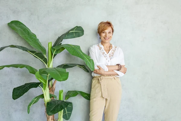 明るい魅力的な女性の肖像画笑顔でStucco背景とともに緑の植物室 — ストック写真