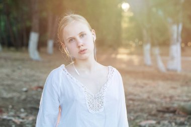 Ormanın arka planında kulaklıklı genç bir kız.