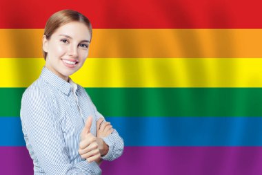 Neşeli genç iş kadını LGBT bayrağıyla baş parmağını gösteriyor..