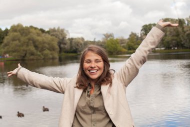 Dışarıda el ele tutuşup doğanın tadını çıkaran genç ve mutlu bir kadın.