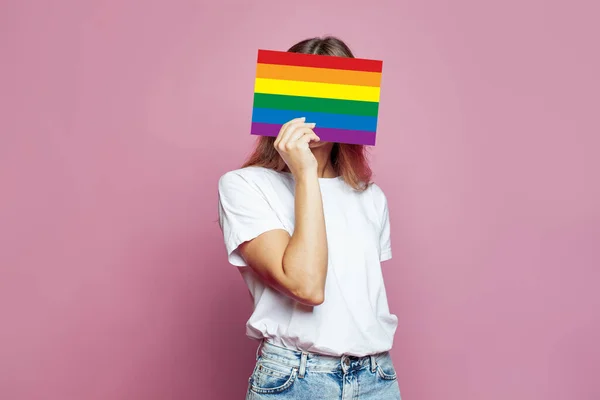 Anonymous woman covering face with LGBT sing on pink background