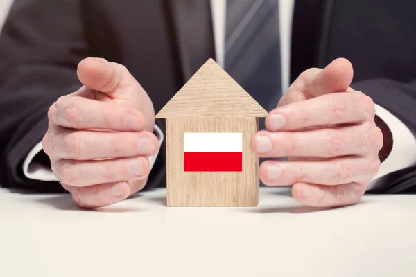 Rączka Biznesmena Trzymającego Drewniany Model Domu Polską Flagą Koncepcje Ubezpieczeń — Zdjęcie stockowe