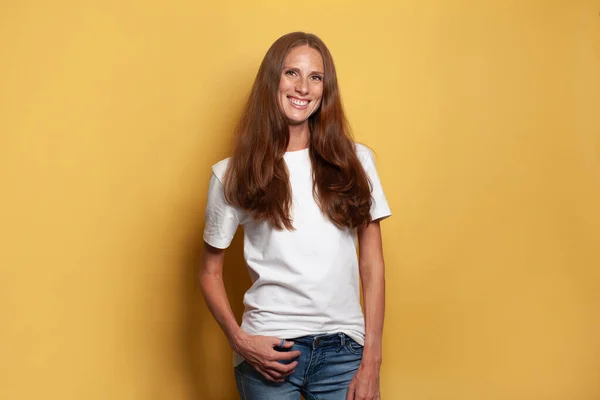 陽気中大人女性でホワイトTシャツに対する黄色のスタジオ壁の背景 — ストック写真