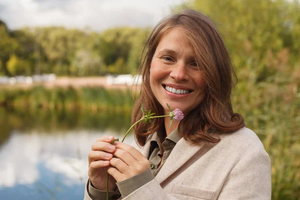 Attraktiv Leende Kvinna Håller Klöver Blomma Utomhus — Stockfoto