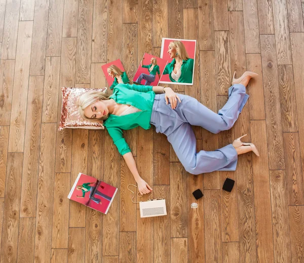 彼女の周りに化粧品や雑誌と枕の上に床に横たわっているファッショナブルなブロンドの女性 — ストック写真