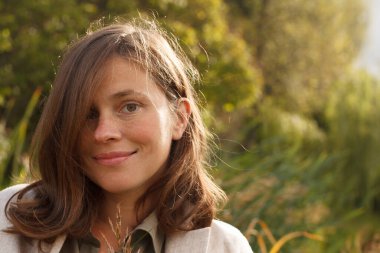 Açık havada kahverengi saçlı, mutlu genç bir kadın, yakın plan portresi.