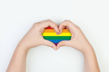 Beyaz arka planda kadın ellerinde LGBT bayrağı olan kalp.