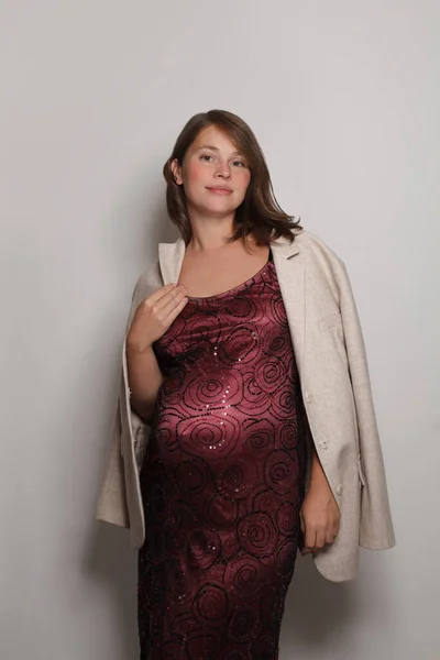 Krásná Okouzlující Těhotná Žena Červené Lesklé Šaty Stojící Proti Bílému — Stock fotografie