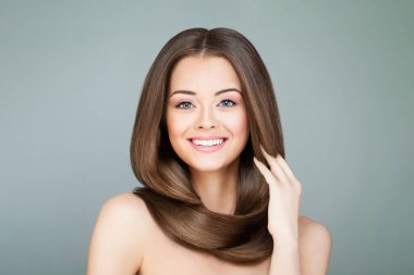 Güzel, genç, esmer, uzun, sağlıklı saçları olan, gülümseyen ve kameraya bakan, moda güzelliği portresi olan bir kadın.