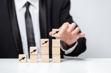 Tahta bloklar, siyah ok simgeleri, el ele tutuşmalar, ticari kazanç kavramı.