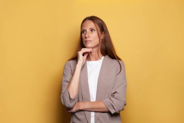 Sarı stüdyo duvarına dayanmış ciddi bir kadın.