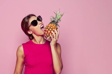 Sağlıklı beslenme ve yaz meyvesi konsepti. Pembe arka planda ananaslı güzel bir kadın.