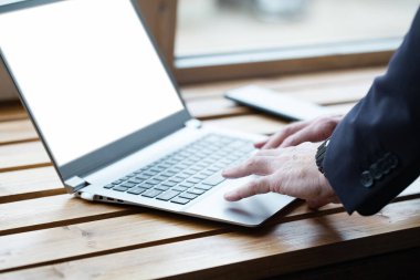 İşadamı elleri daktilo ediyor, dizüstü bilgisayarda çalışıyor. Tahta masaya yakın.