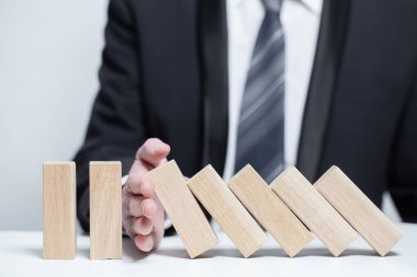 İşletme koruması altındaki tahta bloklar, domino, sigorta emlak konsepti, düşmeyi bırak.