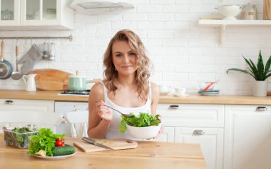 Yemek pişirme ve sağlıklı yeme konsepti. Salata yiyen çekici bir kadın.. 