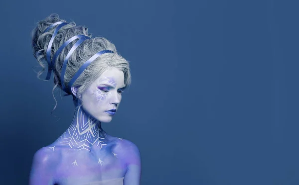 創造的なメイク 完璧なヘアスタイル 青いスタジオの壁の背景に彼女の肌にスノーフレークを描いた豪華な女性スノークイーン カーニバルやハロウィンパーティーメイク スタジオポートレート ストックフォト