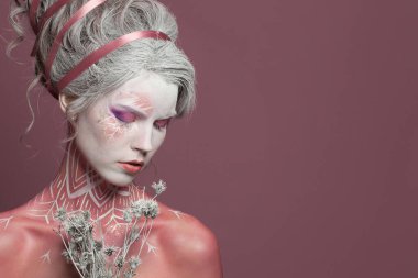 Göz kamaştırıcı Kar Kraliçesi 'nin moda portresi ya da beyaz, mükemmel, fantezi makyajlı Kış Cadısı ve pembe stüdyo duvarlı arka planda boyalı vücut.