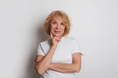 Beyaz stüdyo arka planında gülümseyen neşeli, son sınıf öğrencisi kadın.