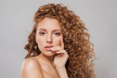 Modaya uygun dalgalı saçlı kadın. Uzun kıvırcık saç stili ve beyaz arka planda poz veren doğal taze ciltli genç manken.