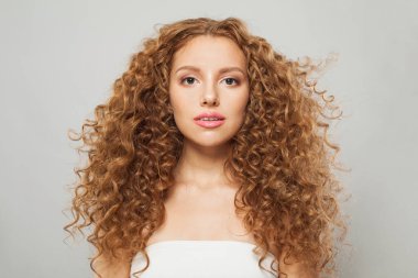 Güzel dalgalı saçlı kadın. Uzun kıvırcık saç stili ve beyaz arka planda doğal taze cildi olan genç, mükemmel bir manken.