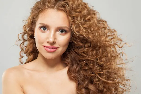 Cheerful wavy hair woman. Young fashion model with long curly hairstyle and natural fresh clear skin posing on white background