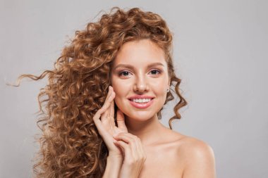 Beyaz arka planda kıvırcık, uzun kahverengi saçlı, kızıl saçlı genç bir kadının moda portresi. Dalgalı saçlı kadın
