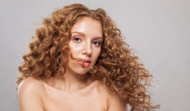 Beyaz arka planda uzun, kıvırcık kahverengi saç stili olan şık, genç bir model. Dalgalı saçlı kadın