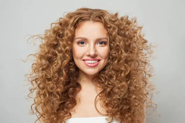 Beyaz arka planda kıvırcık, uzun kahverengi saçlı güzel bir manken. Dalgalı saçlı kadın