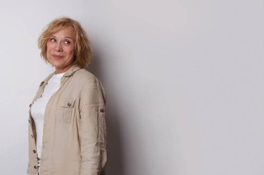 Beyaz stüdyo arka planında duran güzel olgun bir kadın.