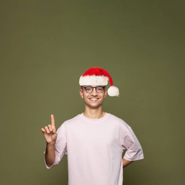 Noel Baba yeşil stüdyo duvarını işaret ediyor.