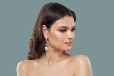 Şık, genç, esmer, mücevher modeli portresi. Uzun kahverengi saçlı, doğal makyajlı, temiz tenli, stüdyo portresi olan bir kadın.
