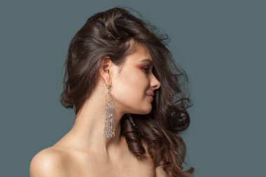 Çekici genç esmer mücevher modeli portresi. Uzun kahverengi saçlı, doğal makyajlı, temiz tenli, stüdyo portresi olan bir kadın.