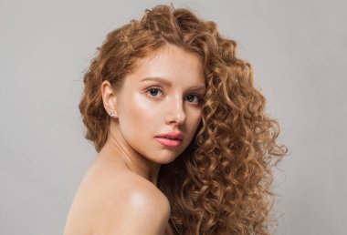 Uzun, sağlıklı, dalgalı saç stili olan genç kızıl saçlı bir kadın, beyaz arka planda mükemmel temiz bir ten, moda güzelliği kavramı.