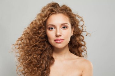 Uzun, sağlıklı, dalgalı saç stili, beyaz arka planda mükemmel temiz cilt, moda güzelliği kavramı olan zarif kızıl saçlı bir kadın.