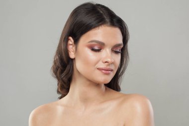 Temiz ciltli sağlıklı bir Fenale modeli. Esmer, mavi arka planda siyah saçlı bir kadın.