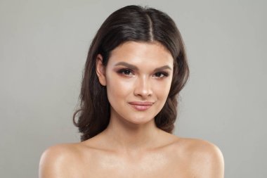 Temiz ciltli sağlıklı bir Fenale modeli. Esmer, mavi arka planda siyah saçlı bir kadın.