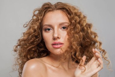 Çekici genç bayan model uzun dalgalı kıvırcık saç stili ve açık tenli stüdyo portresi olan sağlıklı bir kadın. Saç bakımı, yüz tedavisi ve kozmetik konsepti