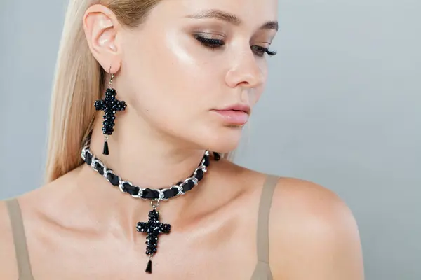 Nice model woman with blonde hair in black jewelry set earrings and choker necklace, closeup portrait